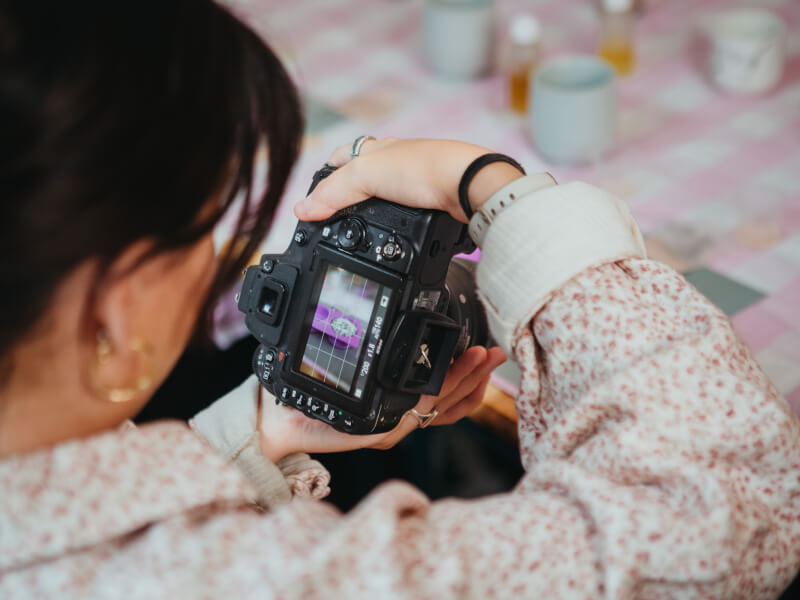 Woman in floral shirt taking a photo on a DSLR camera